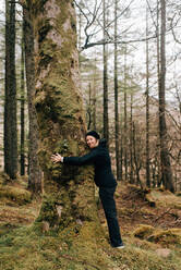 Frau, die einen Baum umarmt, Trossachs National Park, Kanada - CUF52510