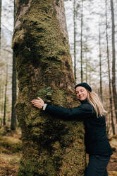 Woman hugging tree, Trossachs National Park, Canada - CUF52511