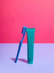 Zahnbürste und Zahnpasta vor rosa und lila Hintergrund - CUF52527
