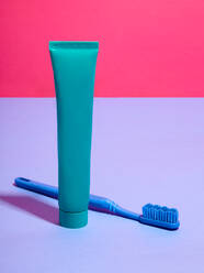 Toothbrush and toothpaste against pink and lilac background - CUF52528