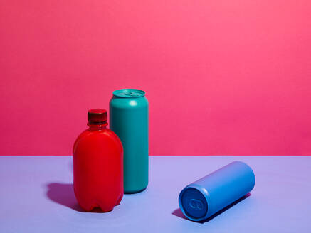 Stilleben aus türkisfarbenen und blauen Getränkedosen mit roter Flasche und rosa Hintergrund - CUF52535