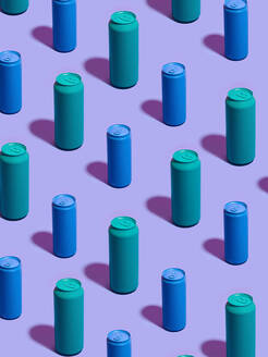 Stilleben mit türkisfarbenen und blauen Getränkedosen in diagonalen Reihen auf lila Hintergrund - CUF52536