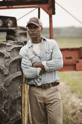 Afroamerikanischer Bauer steht neben Traktor - BLEF07857