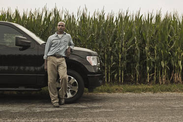 Afroamerikanischer Landwirt lehnt sich an ein Auto neben der Ernte - BLEF07862