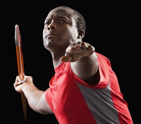 Ein afroamerikanischer Mann hält einen Speer in der Hand - BLEF07872