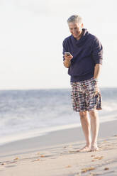 Mann benutzt Mobiltelefon am Strand - BLEF07887