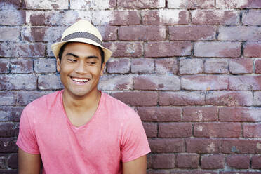 Smiling Asian man near brick wall - BLEF07923