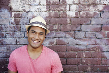 Smiling Asian man near brick wall - BLEF07924