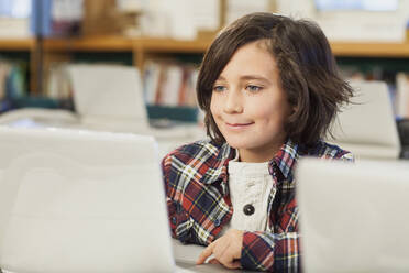 Caucasian boy using laptop in library - BLEF08058