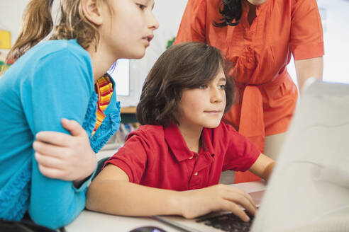 Lehrerin und Kinder benutzen Laptop in der Bibliothek - BLEF08062