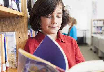 Kaukasischer Junge, der in der Bibliothek ein Buch liest - BLEF08068
