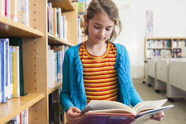 Kaukasisches Mädchen, das in der Bibliothek ein Buch liest - BLEF08069