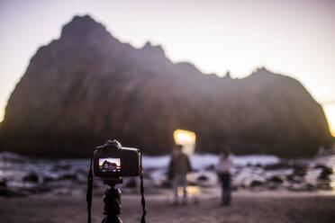 Camera on self-timer taking photograph of couple on beach, Big Sur, California, United States - BLEF08084