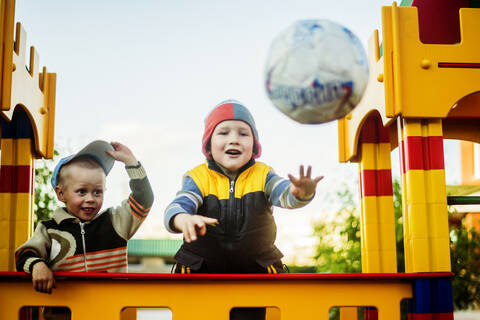 Kaukasischer Junge wirft Ball auf dem Spielplatz, lizenzfreies Stockfoto