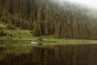 Caucasian man rowing canoe in remote lake - BLEF08129
