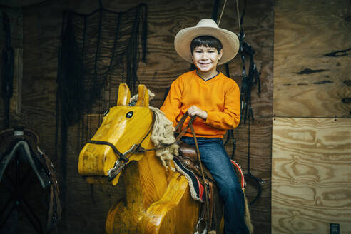 Kaukasischer Junge reitet Spielzeug-Holzpferd - BLEF08185
