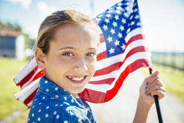 Kaukasisches Mädchen winkt mit amerikanischer Flagge auf einem Bauernhof - BLEF08189