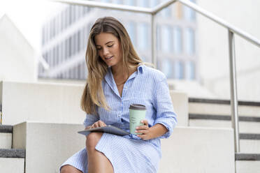 Porträt einer jungen Geschäftsfrau, die ein Tablet benutzt, mit einer Tasse Kaffee zum Mitnehmen - DIGF07100