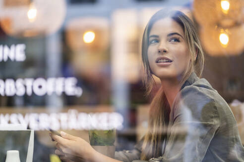 Junge Geschäftsfrau in einem Café, durch ein Fenster gesehen - DIGF07109