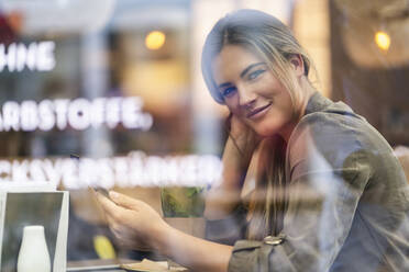 Junge Geschäftsfrau in einem Café, durch ein Fenster gesehen - DIGF07110