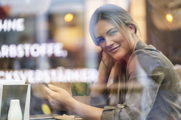 Young businesswoman in a cafe, seen through window - DIGF07110