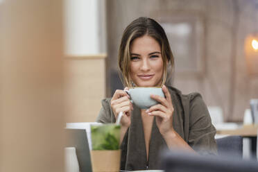 Junge Geschäftsfrau mit Kaffeetasse in einem Cafe - DIGF07116