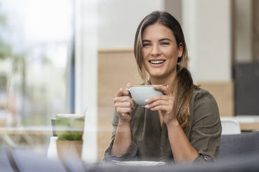 Junge Geschäftsfrau mit Kaffeetasse in einem Cafe - DIGF07118