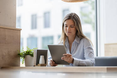 Young businesswoman in a cafe using tablet - DIGF07119