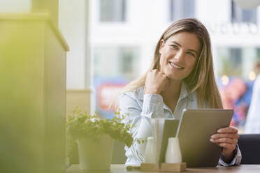 Young businesswoman in a cafe using tablet - DIGF07120