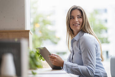 Young businesswoman in a cafe using tablet - DIGF07124