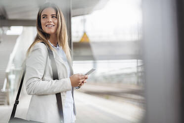 Junge Geschäftsfrau mit Tablet im Stehen am Bahnhof - DIGF07141