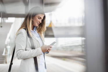 Young businesswoman using tablet standing on station - DIGF07142