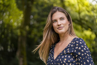 Smiling young woman in park - DIGF07160