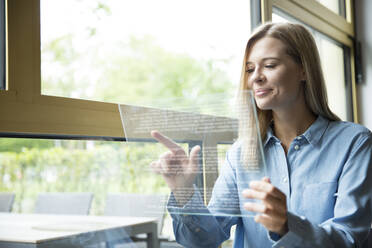 Businesswoman using futuristic tablet, glass pane - MFRF01329