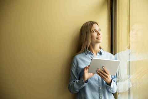 Geschäftsfrau mit Tablet und Blick aus dem Fenster, lizenzfreies Stockfoto