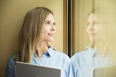 Geschäftsfrau mit Tablet und Blick aus dem Fenster - MFRF01335