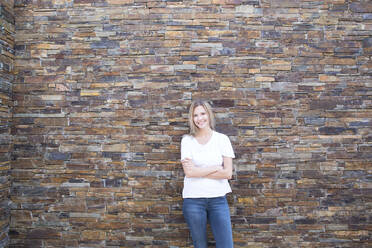 Woman in front of a wall looking at camera, arms crossed - MFRF01343