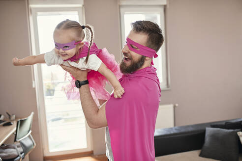 Father and daughter playing superhero and superwoman, pretending to fly - ZEDF02490