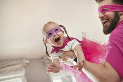 Father and daughter playing superhero and superwoman, pretending to fly - ZEDF02492