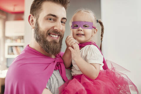 Vater und Tochter spielen Superheld und Superfrau, lizenzfreies Stockfoto