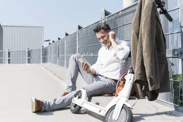 Businessman with E-Scooter and smartphone - UUF18146
