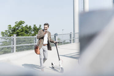 Businessman using hands-free telephone, with E-Scooter - UUF18151