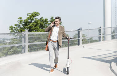 Businessman using smartphone, with E-Scooter - UUF18152