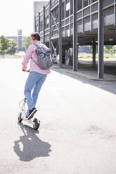 Geschäftsmann mit Rucksack auf seinem E-Scooter - UUF18168