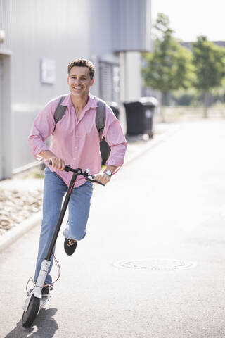 Geschäftsmann mit Rucksack auf seinem E-Scooter, lizenzfreies Stockfoto