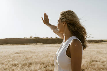 Female traveller holding hand against the sun - ERRF01548