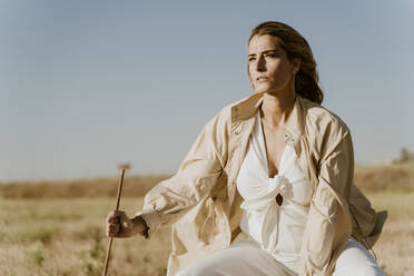 Female traveller sitting on stool, meadow - ERRF01558