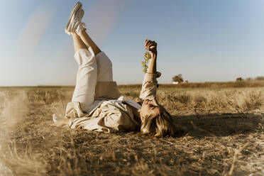 Female traveller lying on meadow, with grapes - ERRF01597