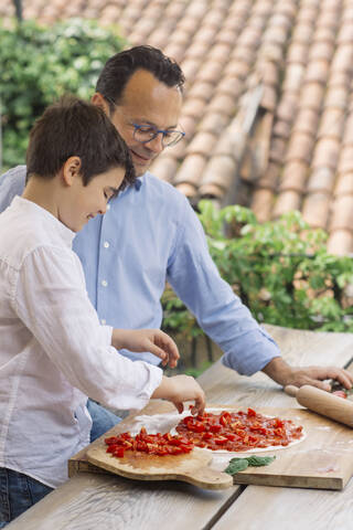 Vater und Sohn bereiten gemeinsam eine Pizza zu, lizenzfreies Stockfoto