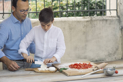 Vater und Sohn bereiten gemeinsam eine Pizza zu, lizenzfreies Stockfoto